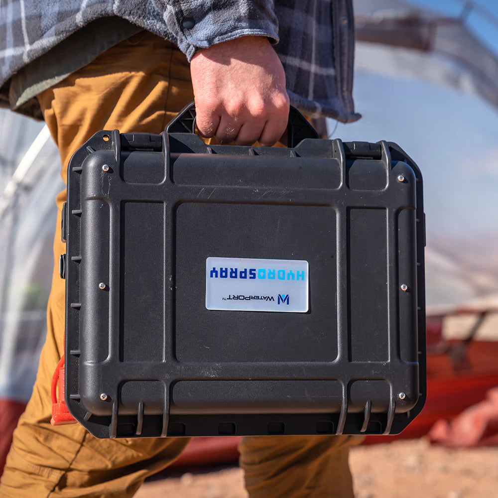 Person carrying black weatherproof case with 'HydroSpray' branding in a natural environment